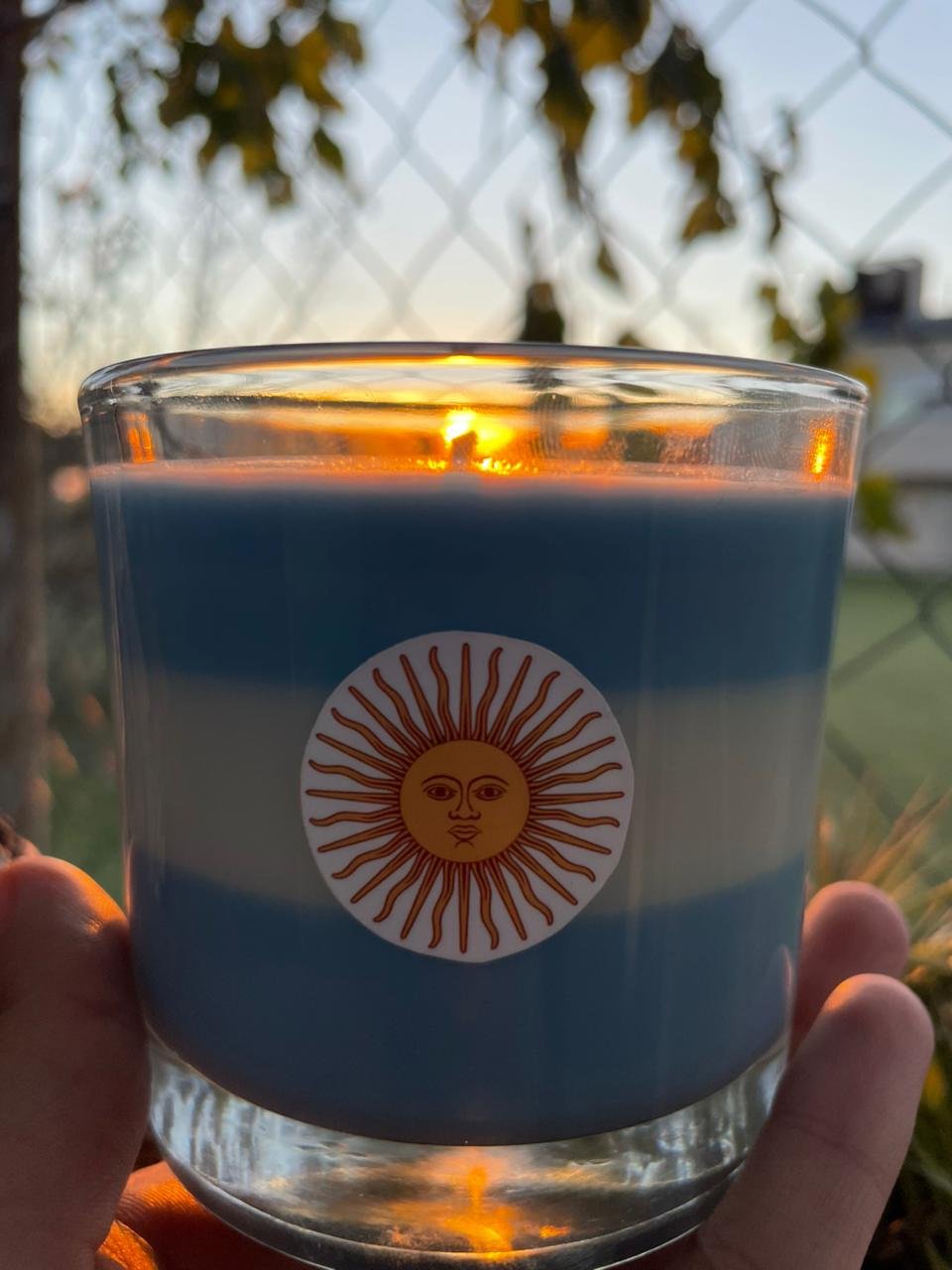 Primer plano de vela aromática celeste y blanca con el Sol de Mayo de Svelas para decoración del mundial.