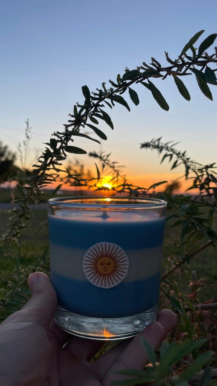 Vela de soja argentina edición limitada mundial sostenida al aire libre durante la puesta de sol.
